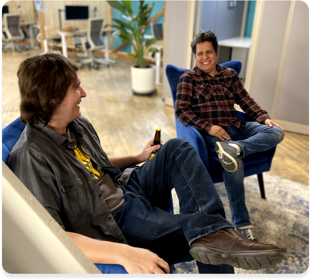 Two businessmen seated in office chair, having a conversation.