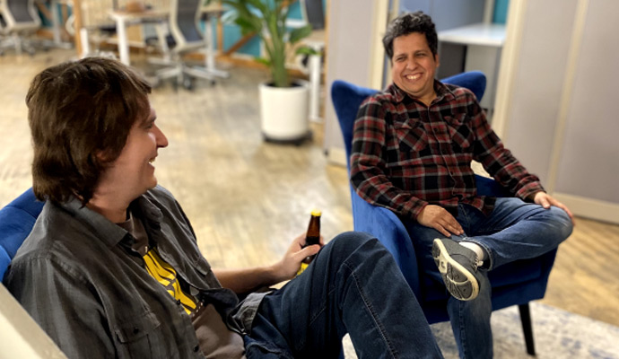 Two businessmen seated in office chair, having a conversation.