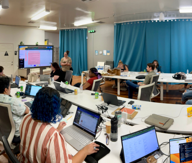 A team of professionals working together at a table with laptops, showcasing diversity and teamwork.