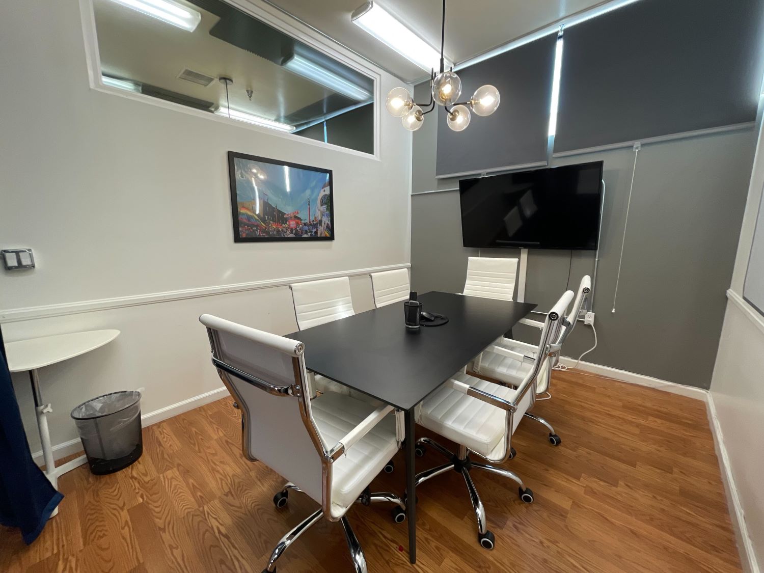 A  modern conference room with a large white desk at the center, surrounded by several chairs.