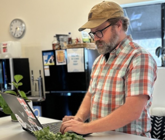 A man and woman sitting at a table with a laptop, working together on a project.