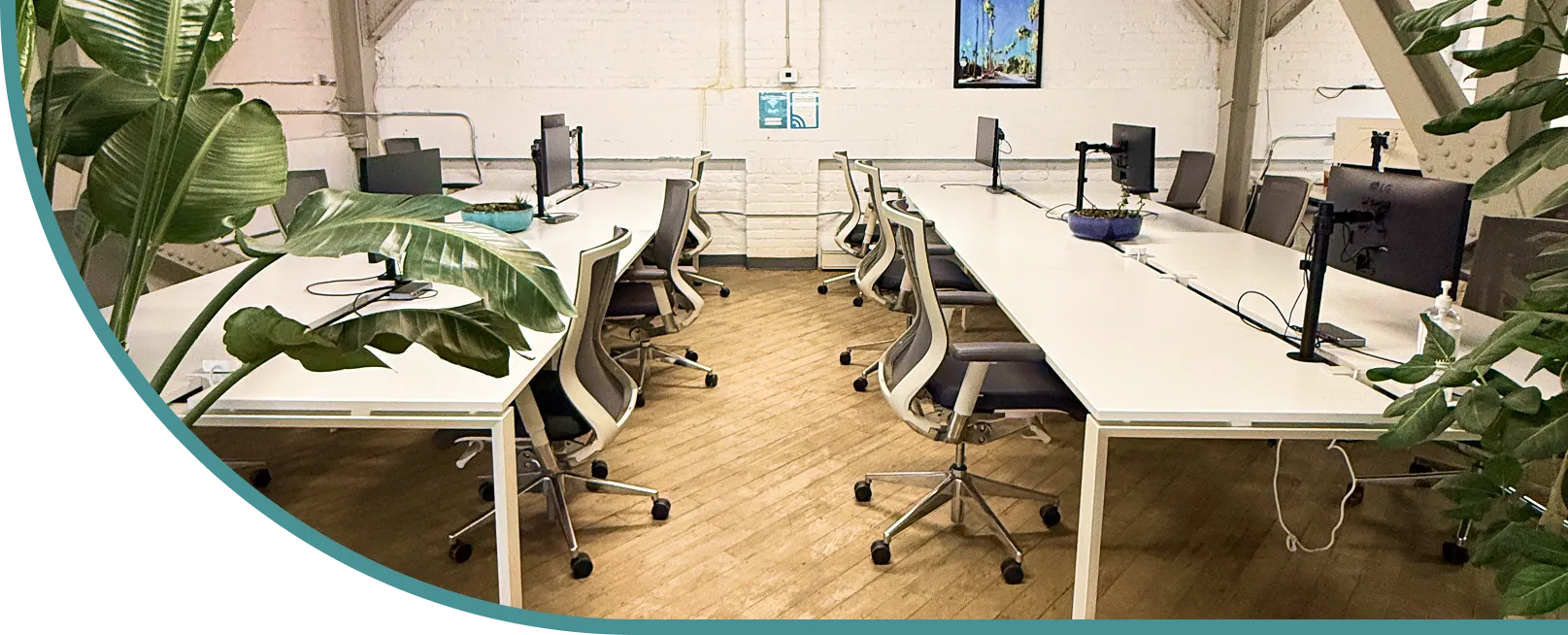 Modern coworking space at Explore Digital with bright, neutral lighting, white desks, ergonomic chairs, indoor plants, and exposed brick walls.