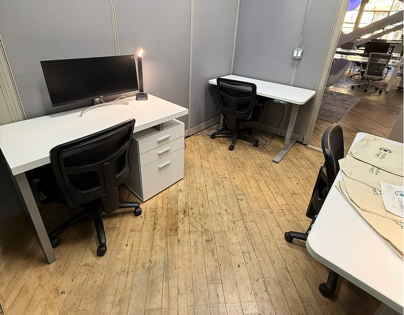Modern office space with Hillcrest signage, blue bar stools at a window-facing desk, lush vertical wall planters, and bright industrial lighting.