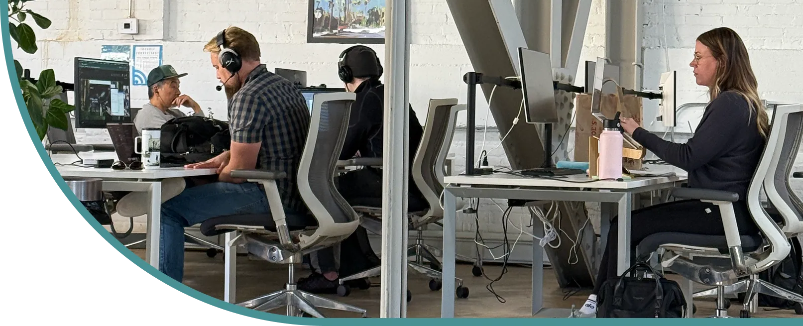 Diverse team works in bright, modern office with industrial decor. Includes HyperX headset and Joe’s branding; laptops and ergonomic chairs featured.